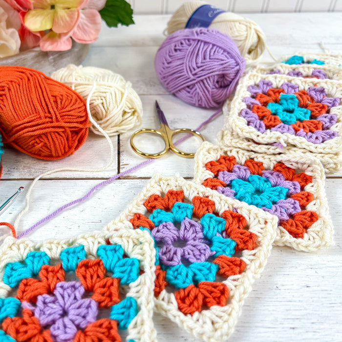 Two Crochet Motifs in Green and Orange Tones, Four Skeins of Yarn, Crochet  Hook and Small Scissors on Beige Backgr…